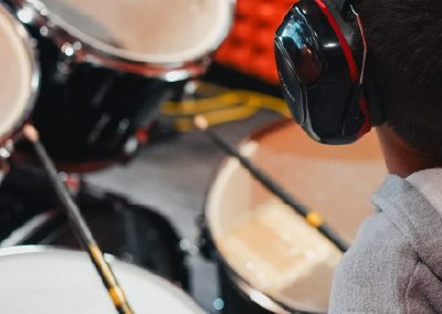 Alumno en clase de batería acústica usando protectores auditivos en salón especializado de MVS Music Center en CDMX, Querétaro, Estado de México y Los Cabos