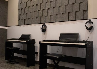 Salón acústico con dos pianos digitales y estaciones individuales para clases de piano en MVS Music Center en CDMX, Querétaro, Estado de México y Los Cabos